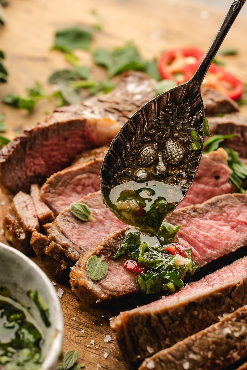 Spooning the chimichurri sauce over top of the steak.
