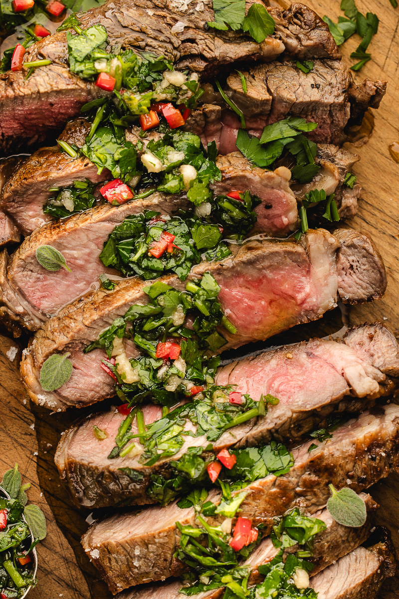 A skillet ribeye steak sliced up on a cutting board.