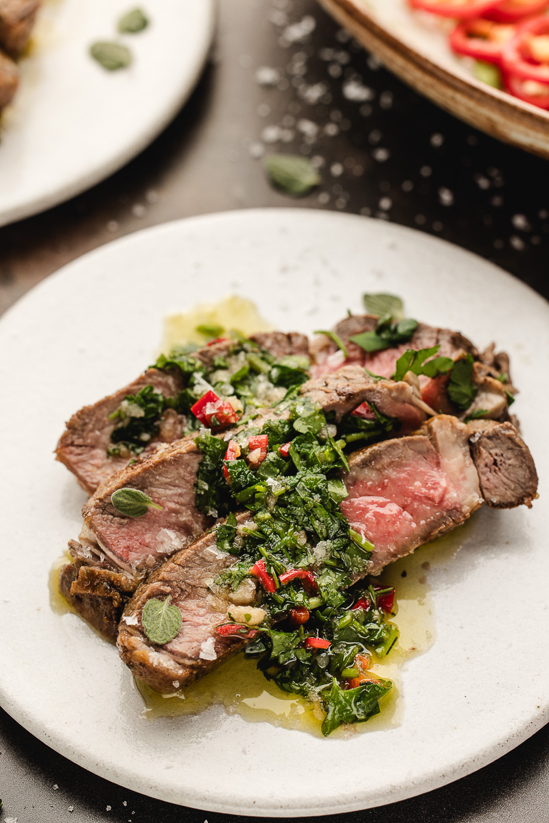 A plate with skillet ribeye steak with chimichurri sauce.