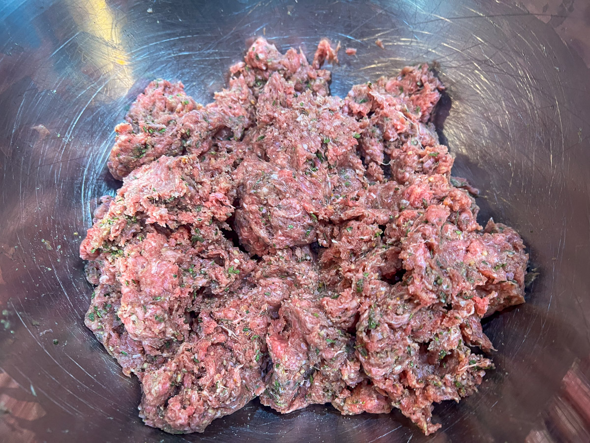 Meatball mixture mixed in a stainless steel bowl.