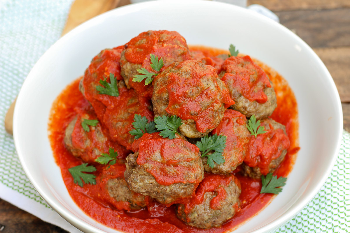 Skillet meatballs tossed in pasta sauce in a white serving bowl garnished with fresh parsley.