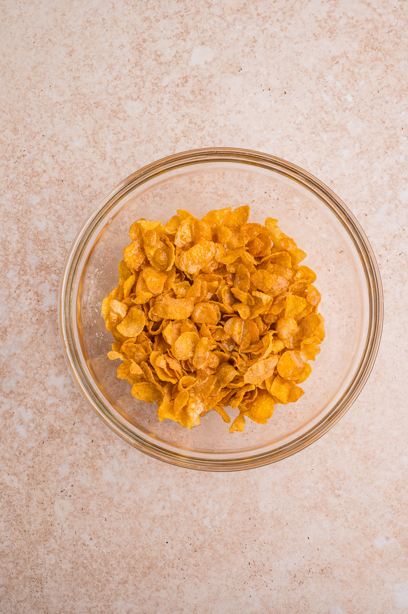 Cornflakes and melted butter mixed together in a bowl.