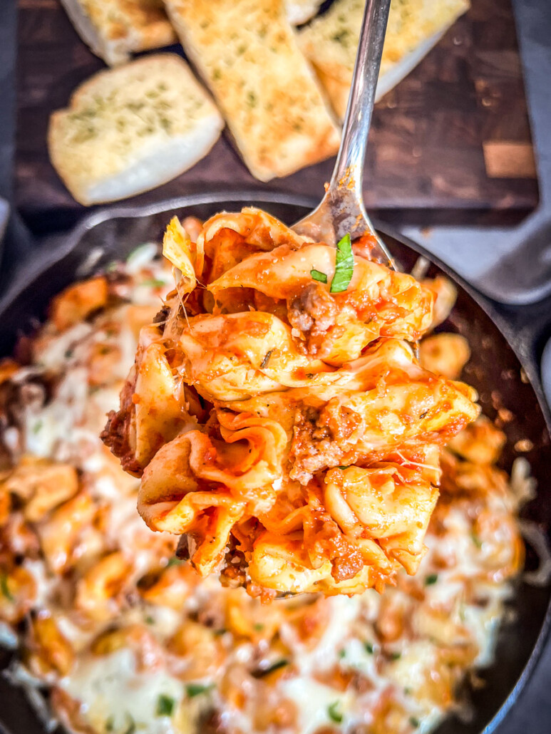 Image of sausage tortellini skillet with a serving spoon portion raised above the pan.