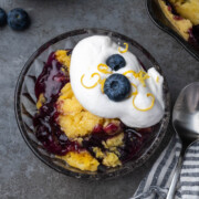 Blueberry lemon dump cake in a bowl with whipped cream on top.
