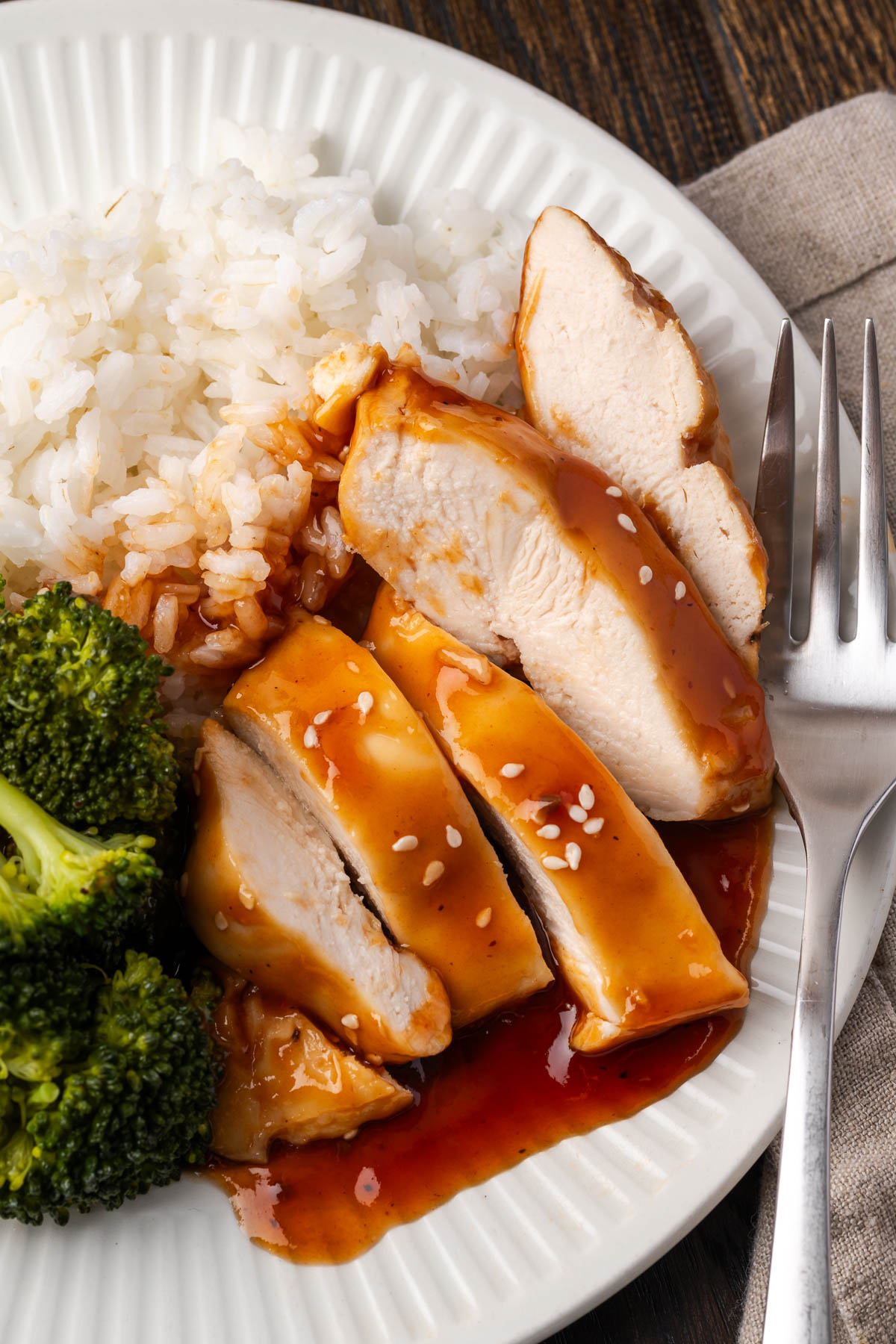 BBQ teriyaki chicken, rice, and broccoli sliced on a plate.
