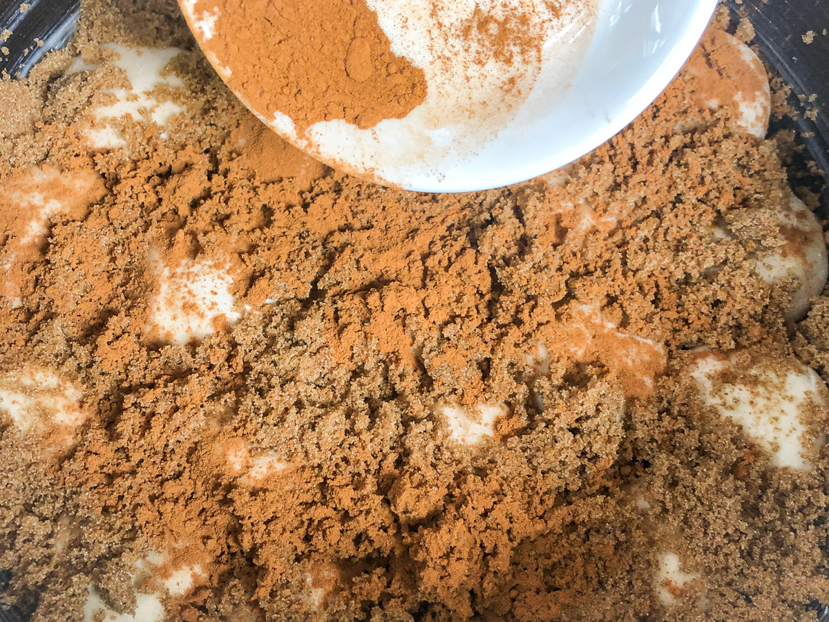 Adding brown sugar and cinnamon to the top of the rolls.