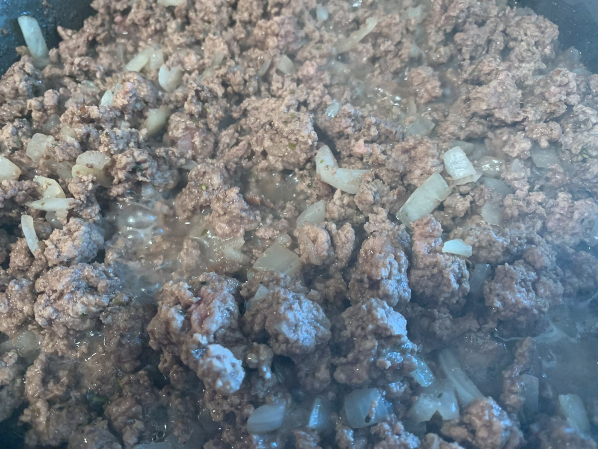 Cooking the ground beef with the onions.