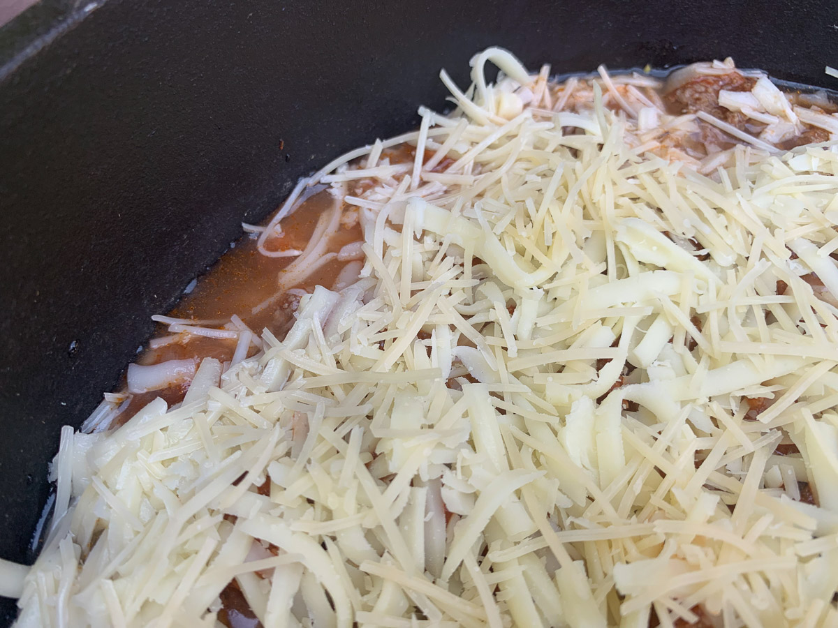 Lasagna topped with cheese and water added.