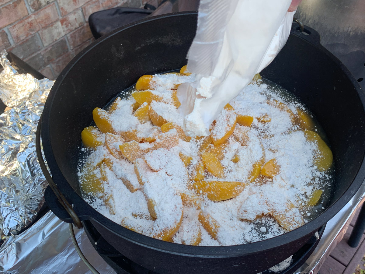 Cake mix being poured over peaches.
