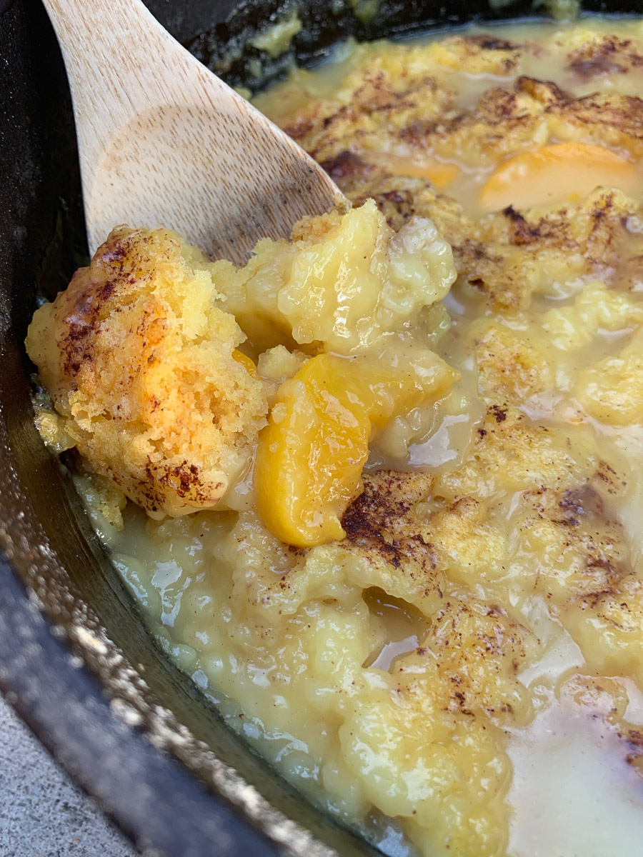 Peach dump cake being picked out of the dutch oven.