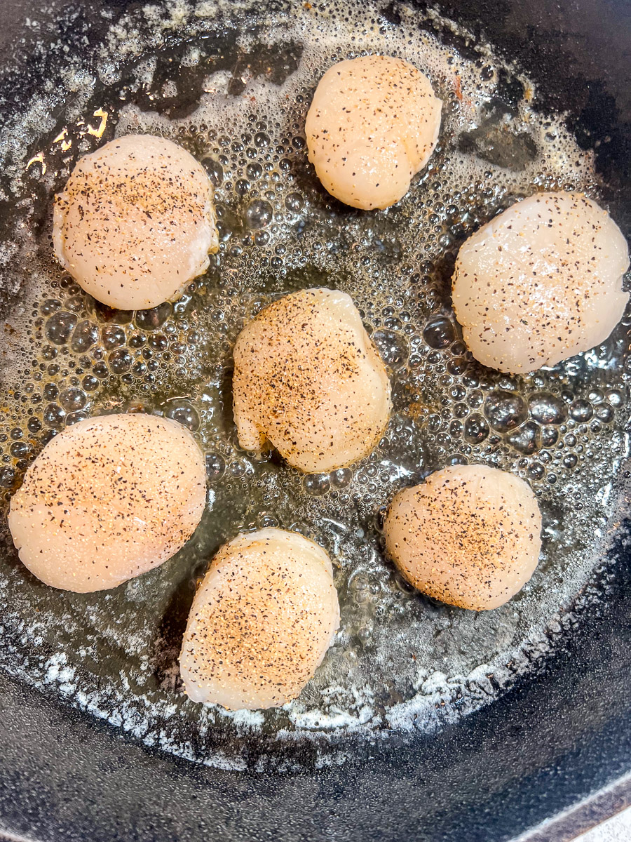 Scallops searing in butter in the skillet.