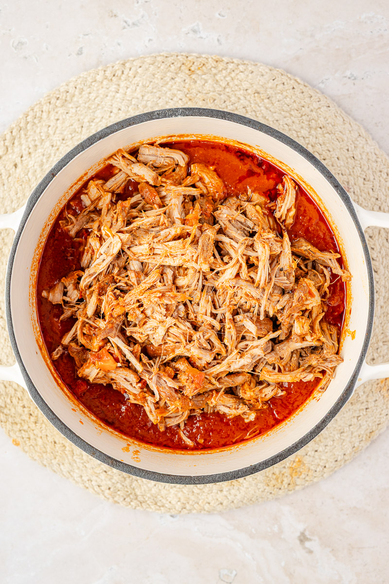 Shredded pork added to the pot of ragu.