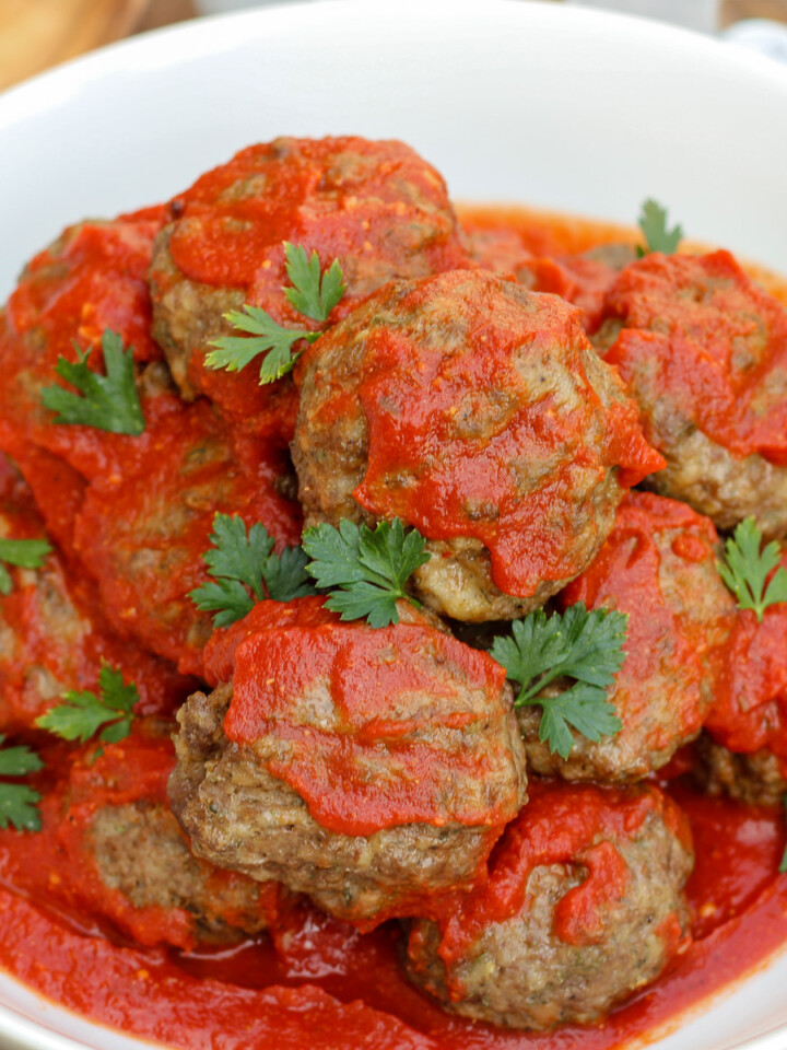 A bowl of skillet meatballs in Italian tomato sauce and garnished with chopped parsley.