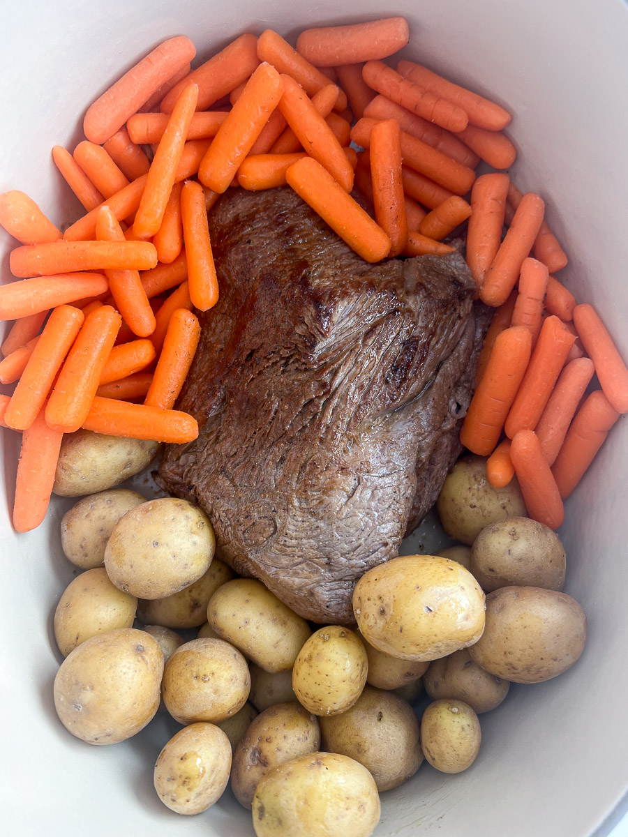 Baby golden potatoes and baby carrots around the beef roast.