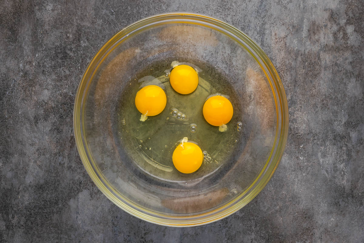 Four cracked eggs in a bowl.