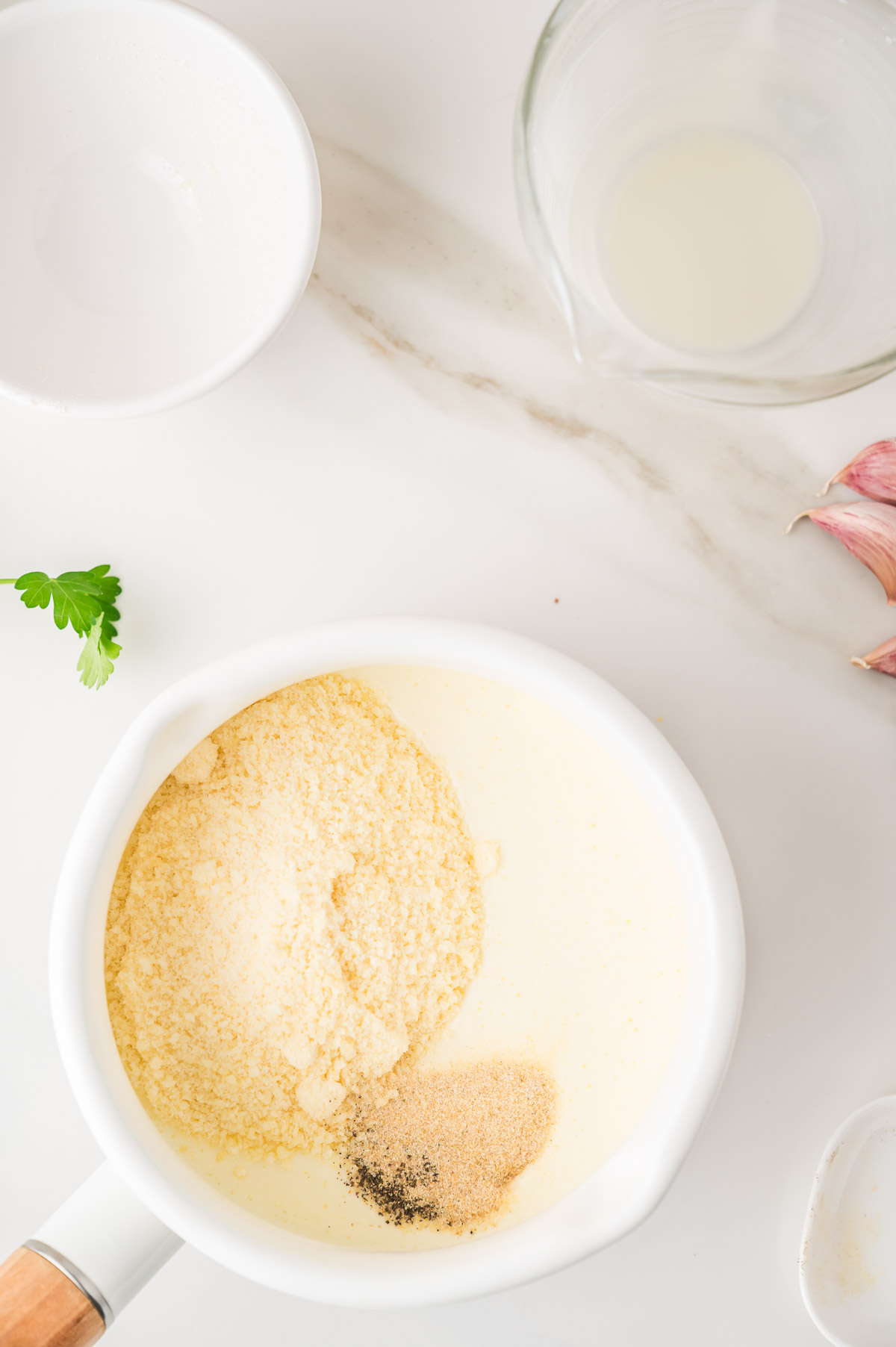 Creamy alfredo sauce thickening in a saucepan with parmesan cheese