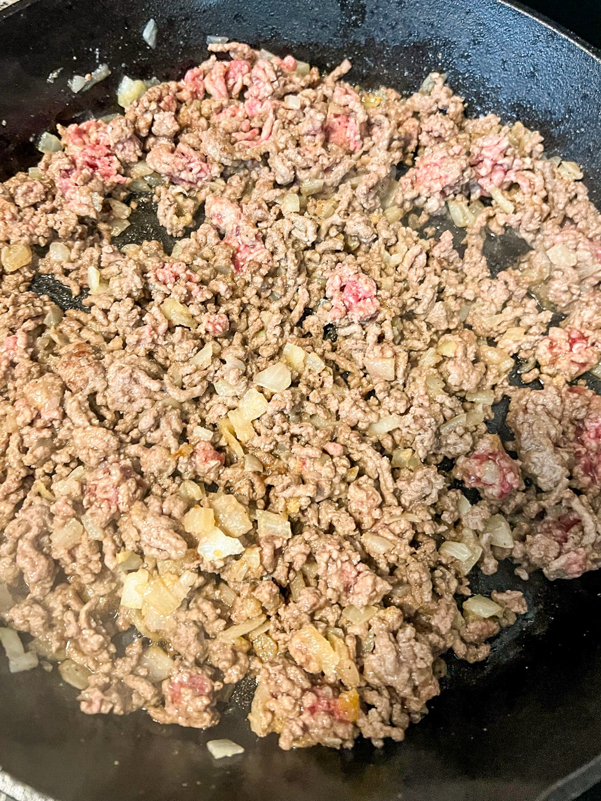 Ground beef and onions cooking in a skillet.