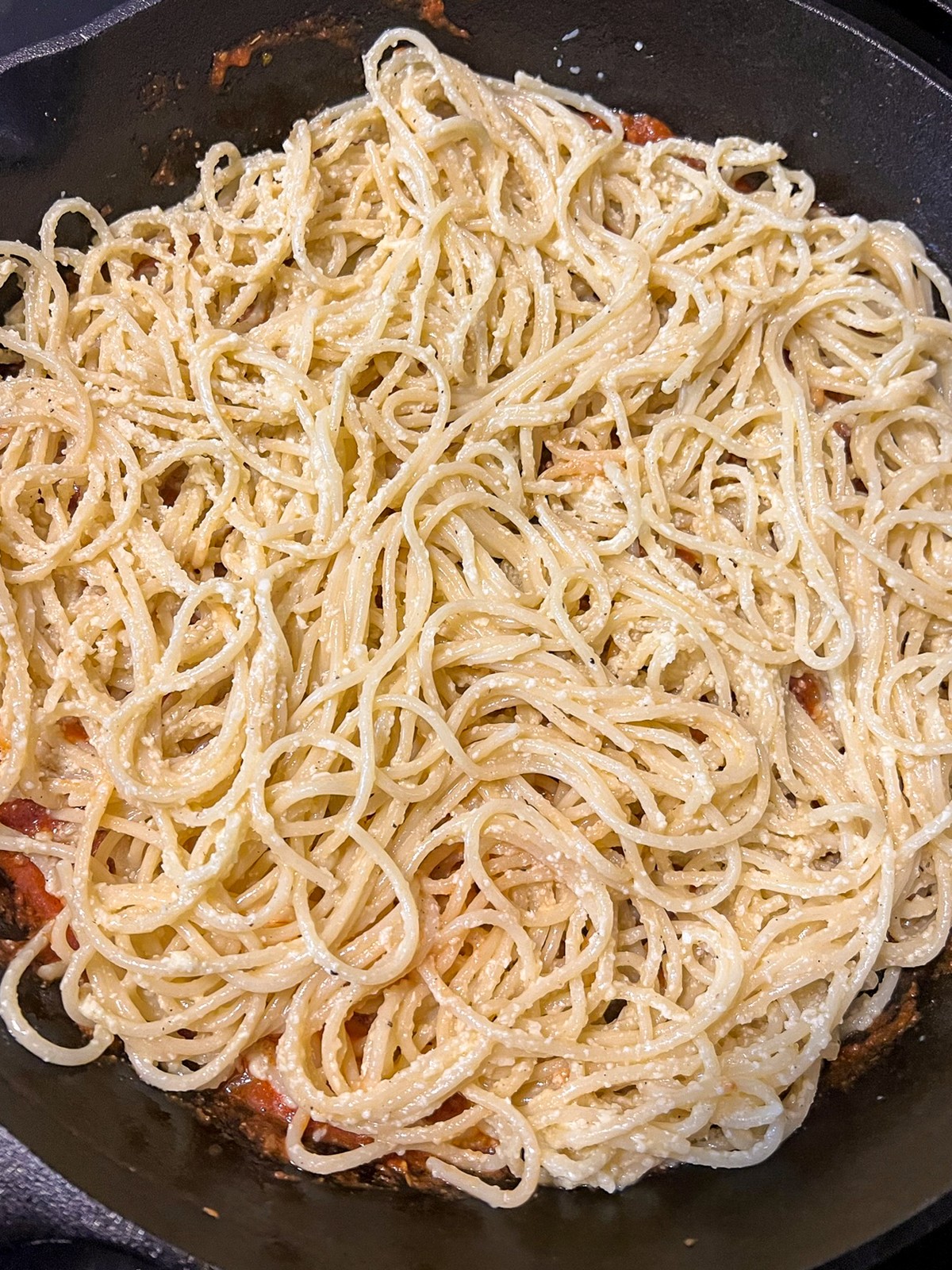 A layer of coated spaghetti covering the bottom of the skillet.