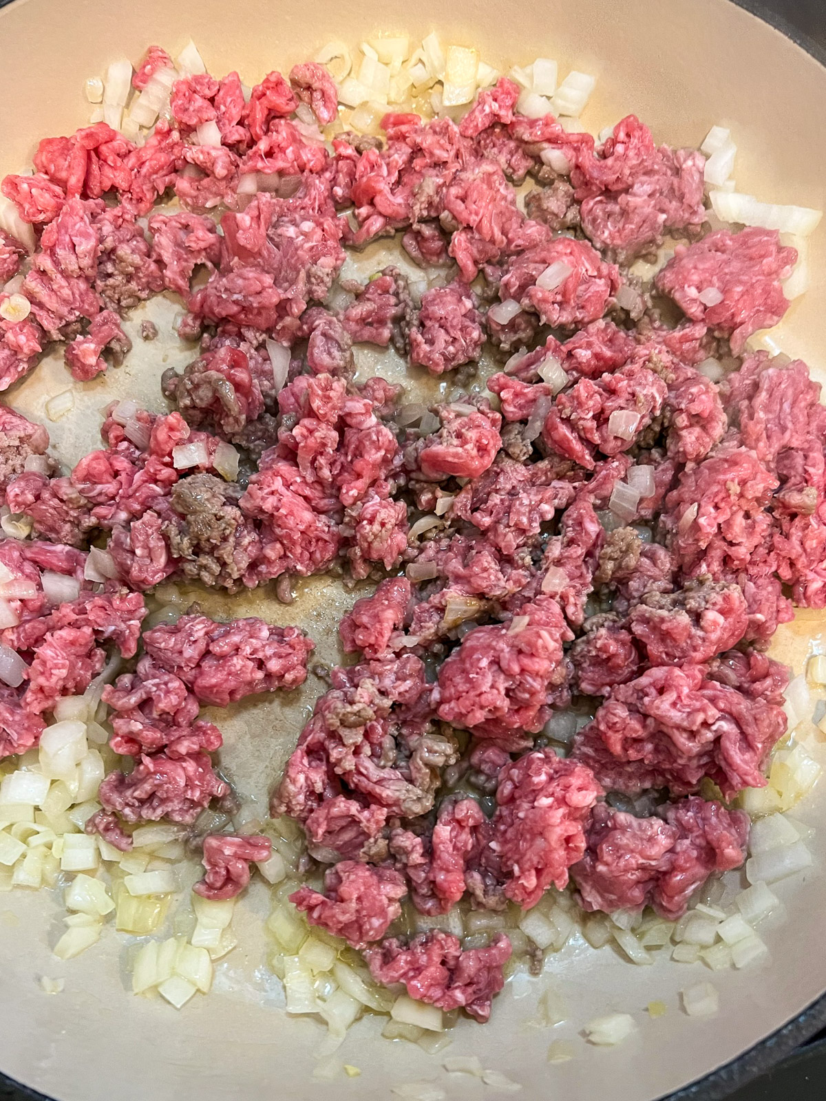 Ground beef browning in a cast iron skillet.
