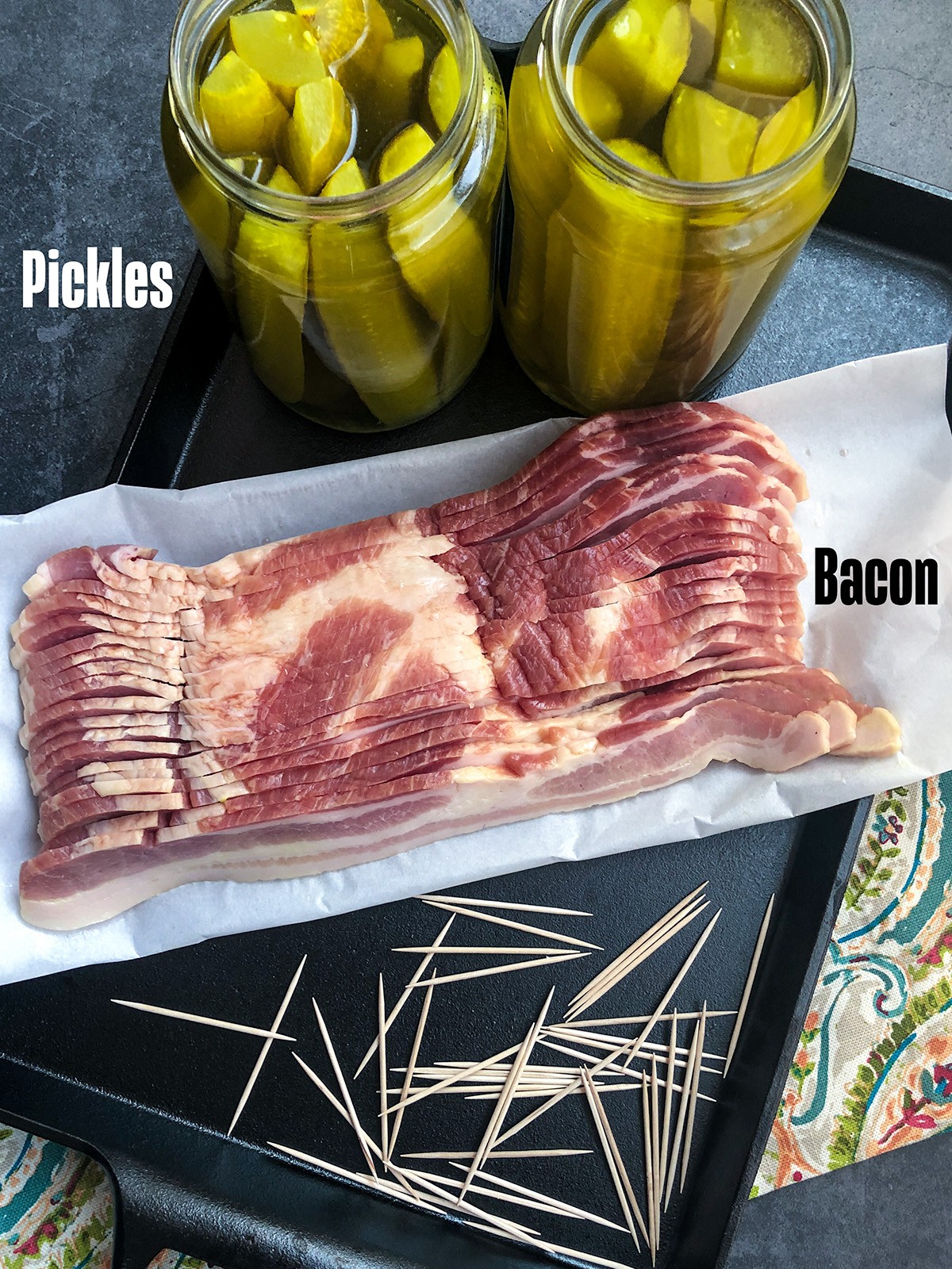 Ingredients for cast iron bacon wrapped pickles laid out on a counter.