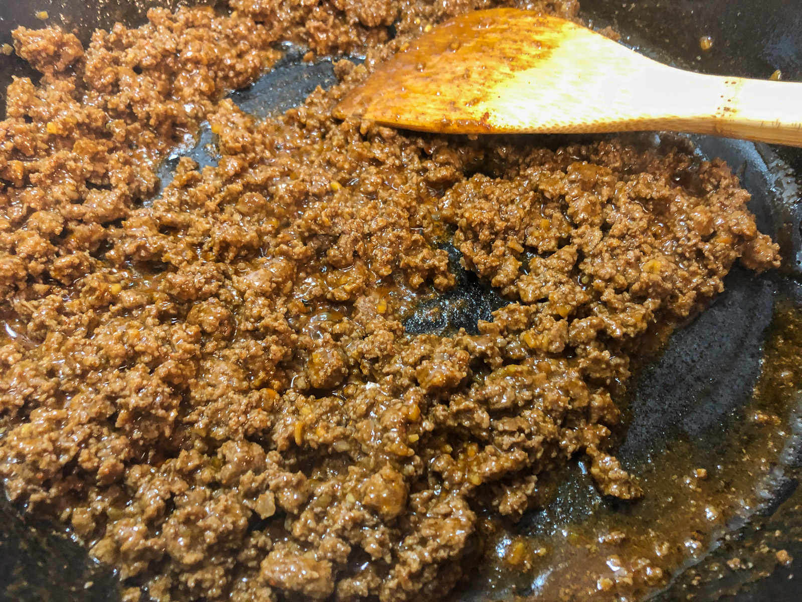 Browned ground beef with taco seasoning in a cast iron skillet for skillet nachos