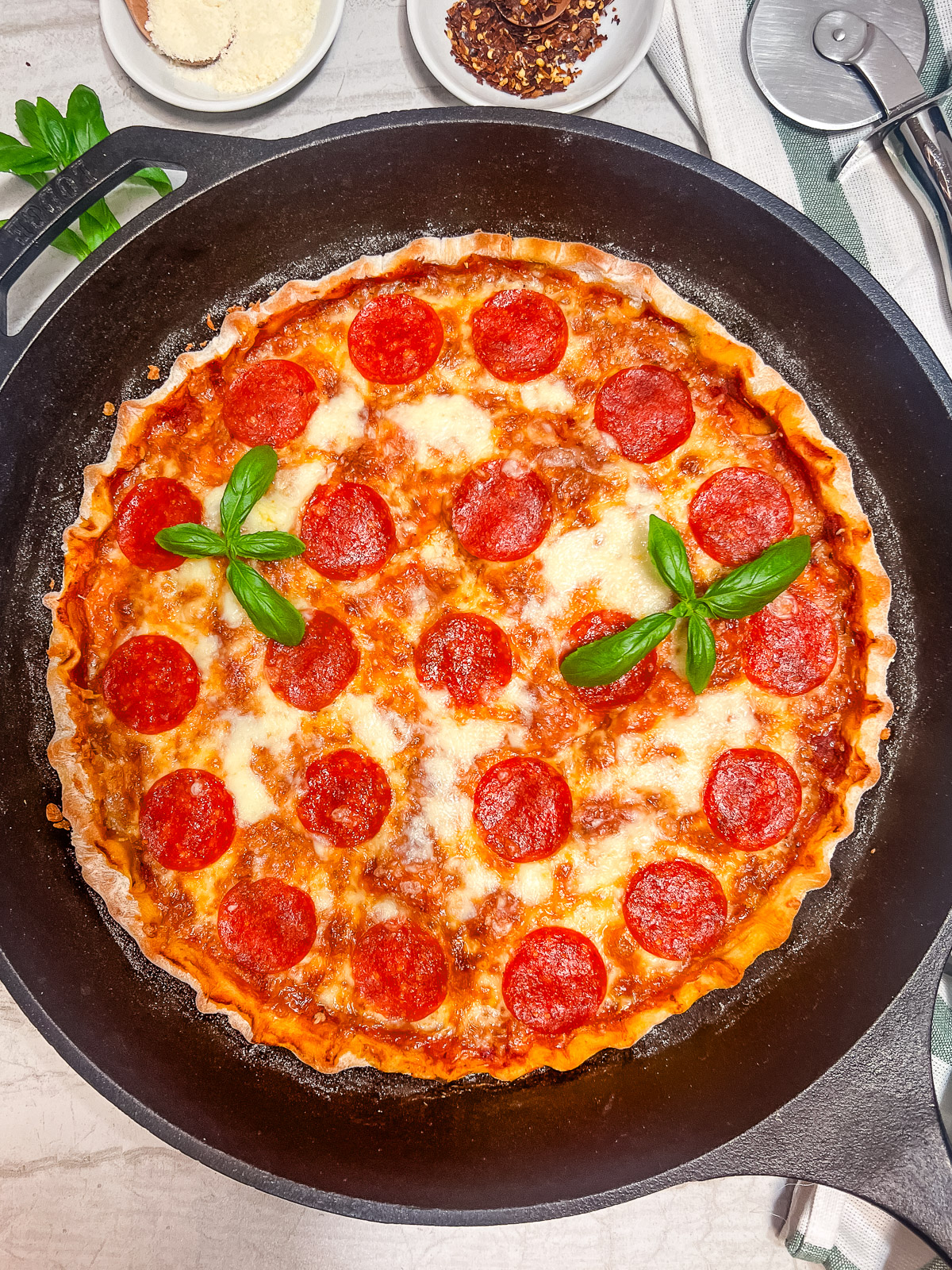 A cast iron pizza garnished with fresh basil.