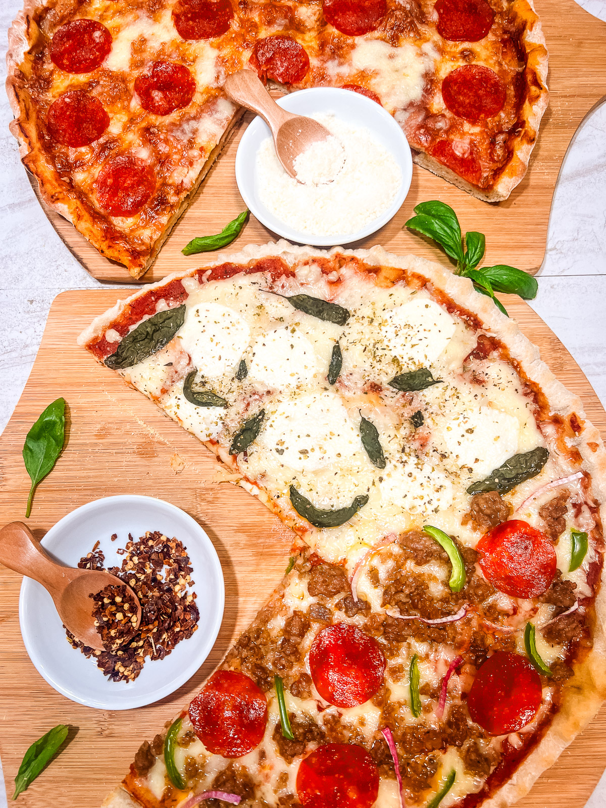 Pizzas with a variety of toppings on a board with slices missing.
