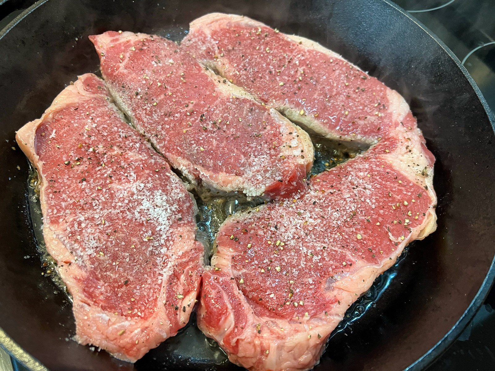 Perfectly seared and cooked steak garnished with fresh rosemary in a skillet.