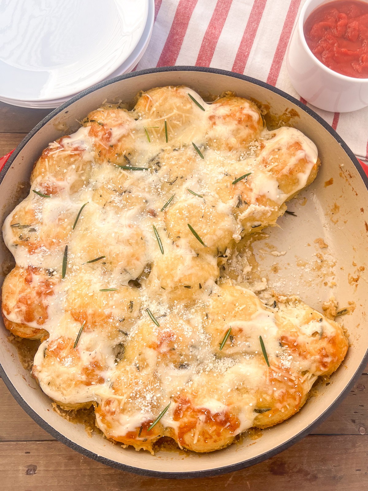 Cheesy Alfredo Pull Aparts being displayed in an uncovered Dutch Oven. Three of the pull aparts have been already served.