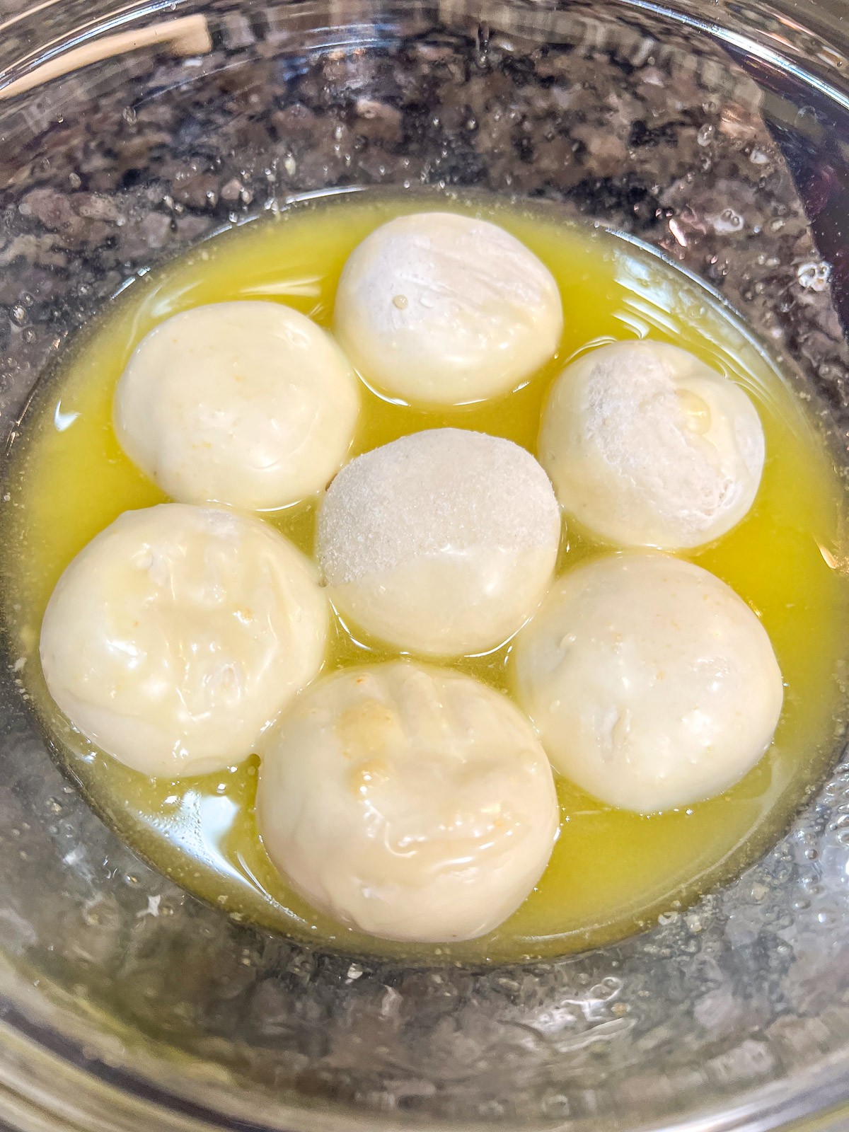 Frozen rolls being dipped into melted butter.