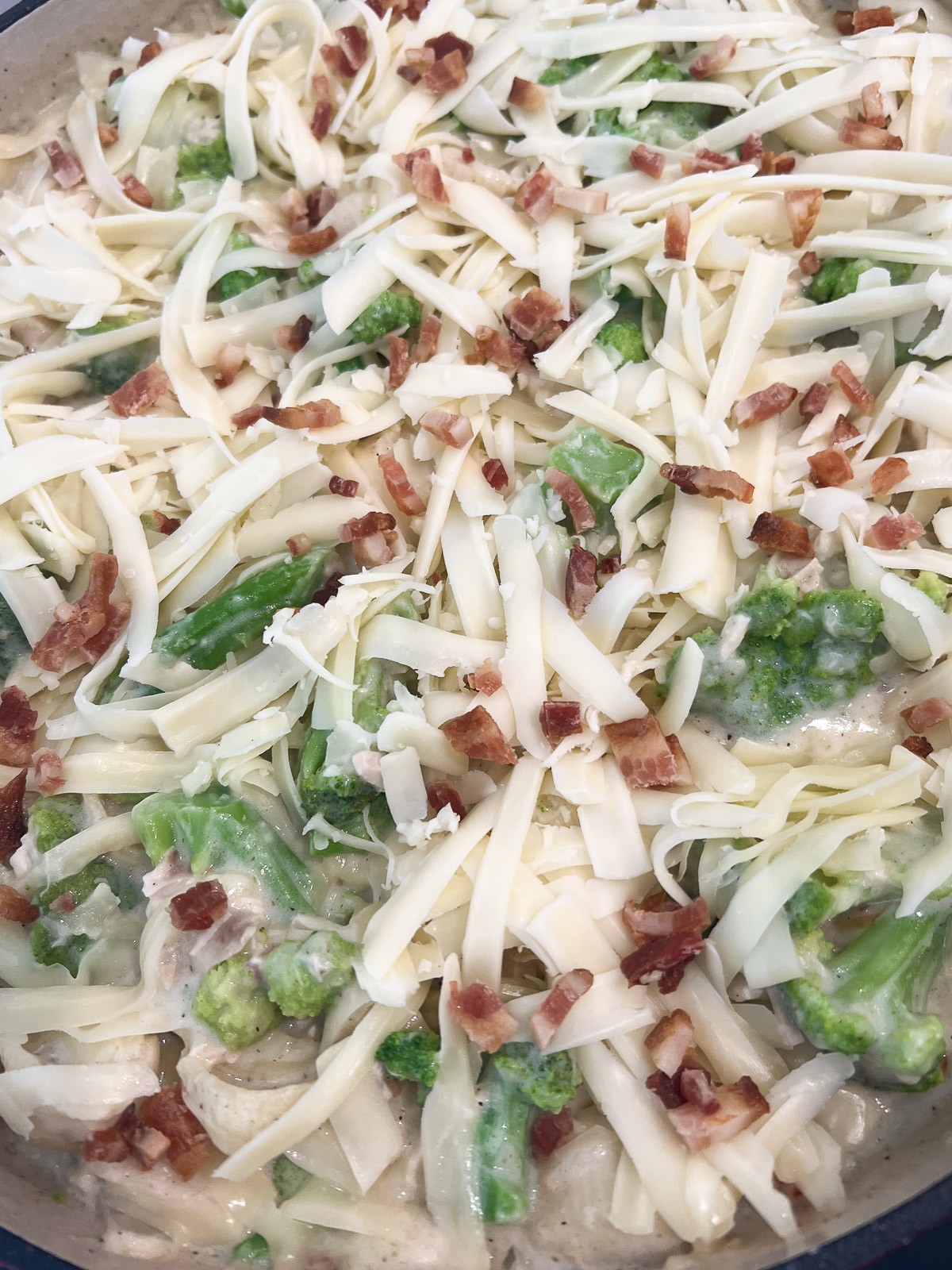 The chicken broccoli pasta topped with more mozzarella cheese and bacon crumbles before baking.