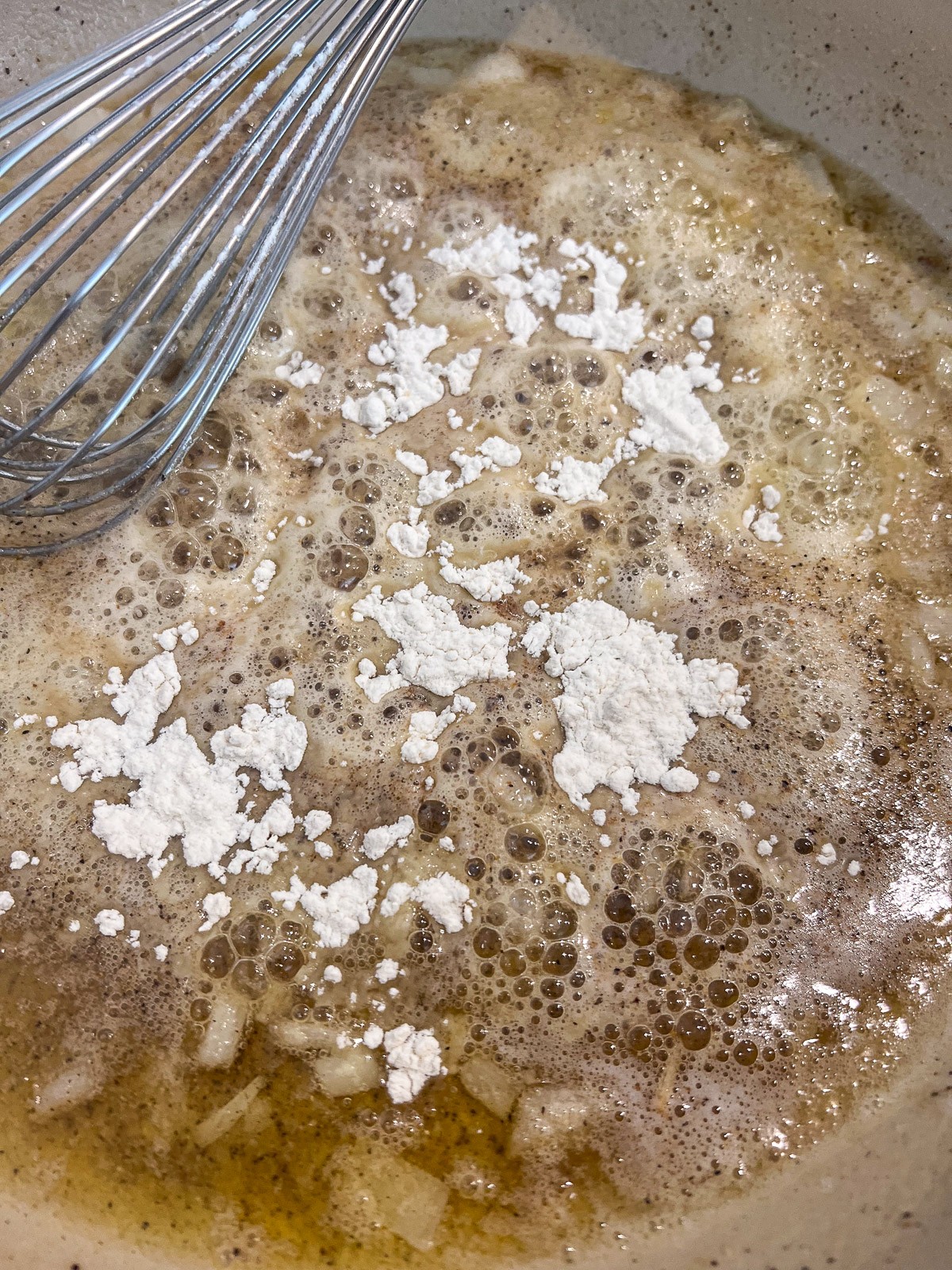 Flour being whisked into the sauteed seasoned butter to make a roux.