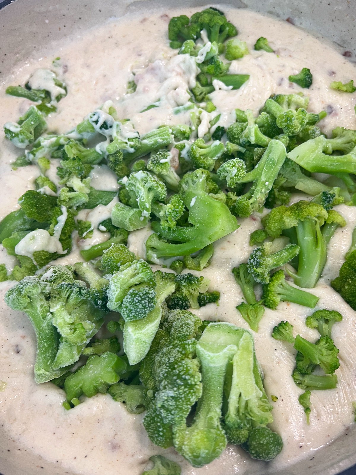 Broccoli florets being added to the cheese sauce.