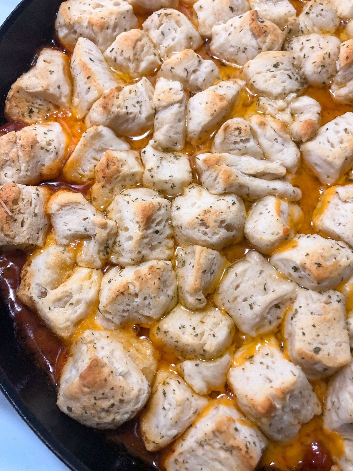 Baked cast iron skillet with chili, cheese and hotdogs, topped with a seasoned biscuit top.