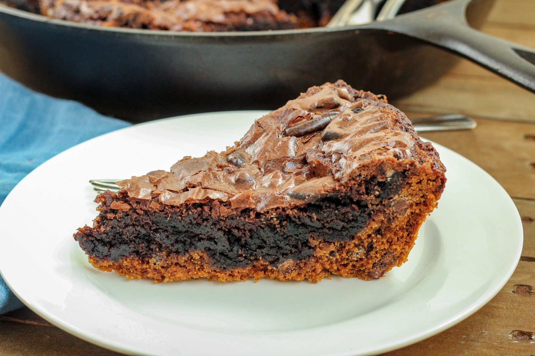 A pie-shaped piece of the brookie in the cast iron skillet with several forks.