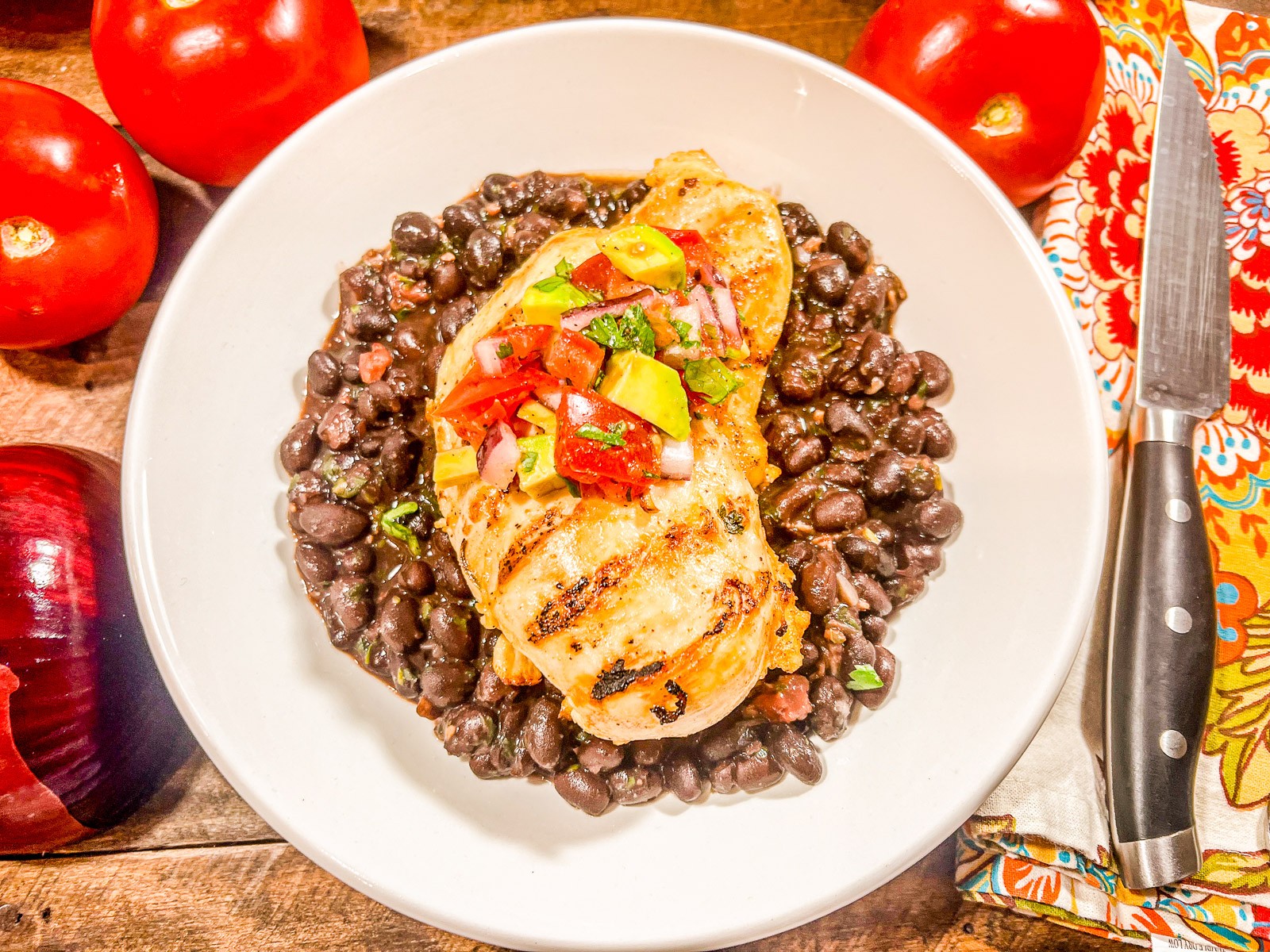Four pan grilled chicken breasts on a white platter.