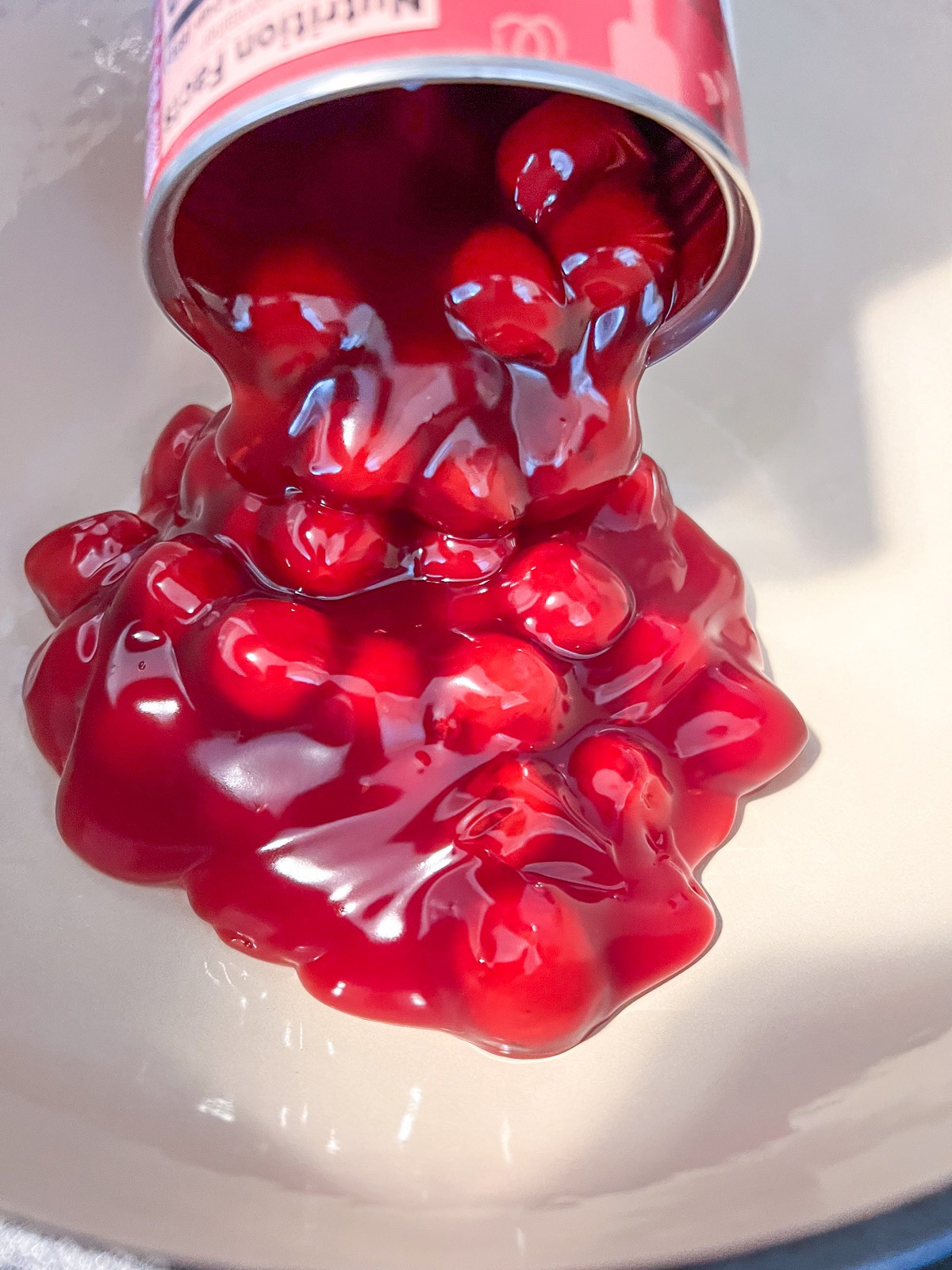 Devil's Food cake mix being sprinkled over the cherry pie filling in the dutch oven.