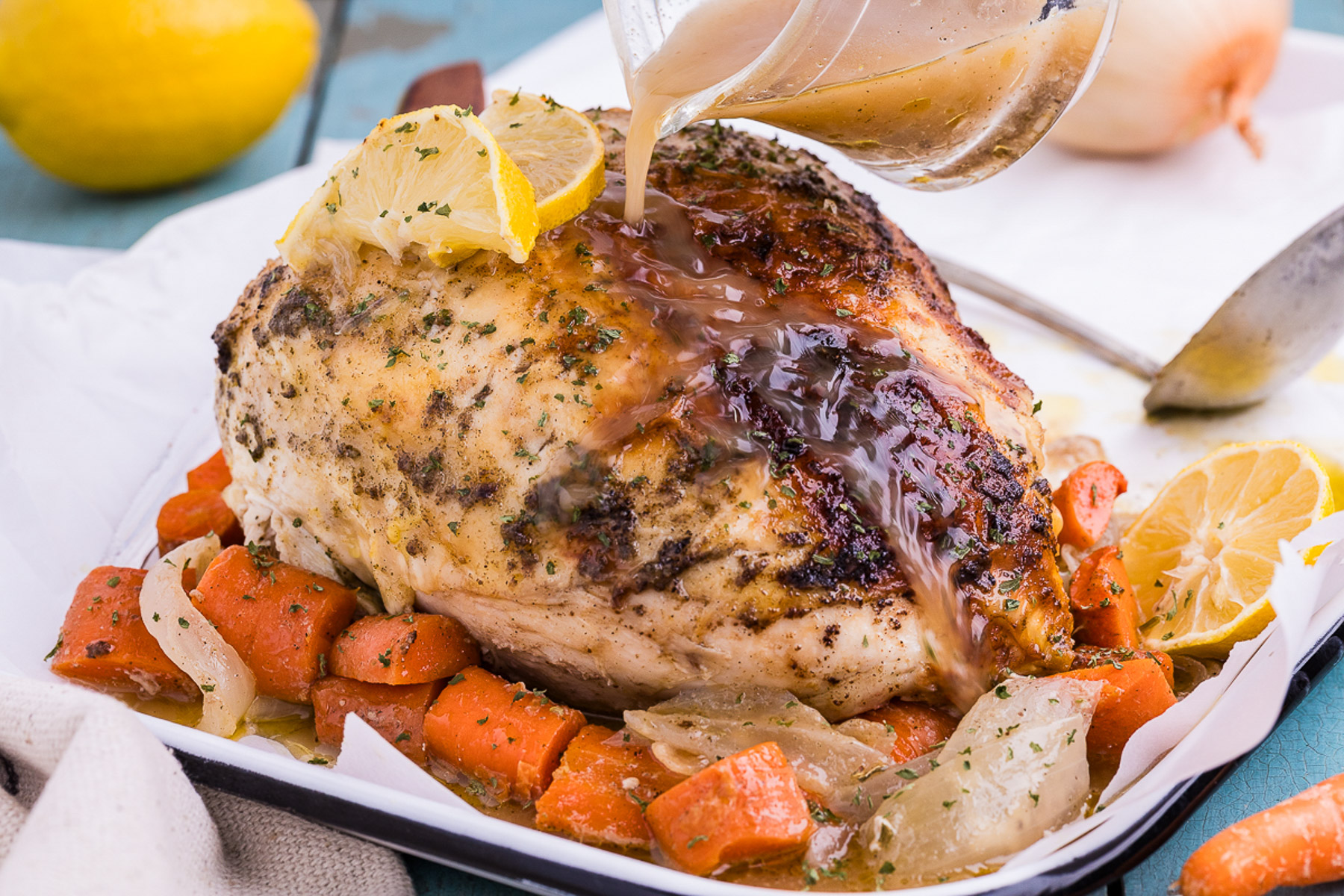 Side view of sliced dutch oven chicken with lemon herb butter and roasted carrots