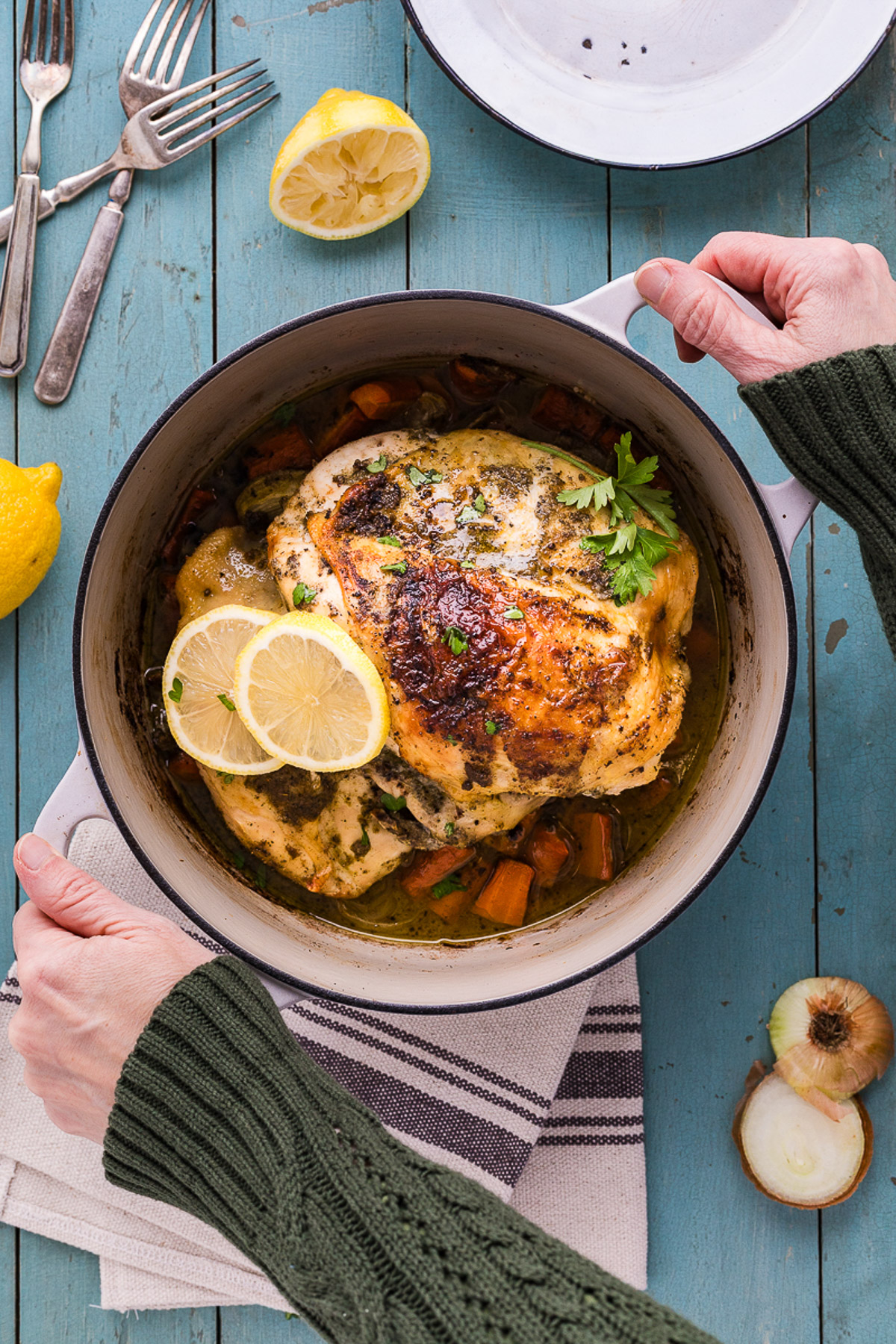 Finished dutch oven chicken recipe with golden lemon herb butter skin and roasted carrots and onions