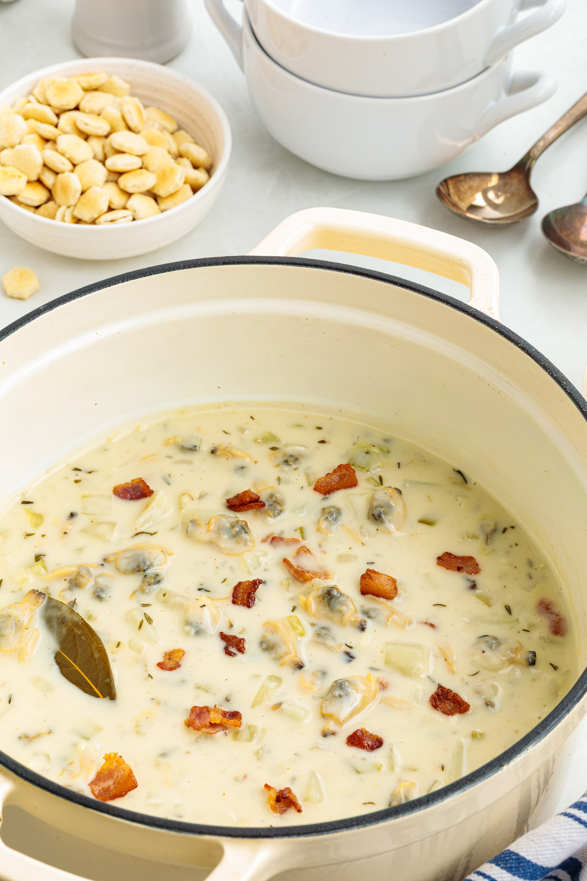 A pot of New England clam chowder garnished with bacon.