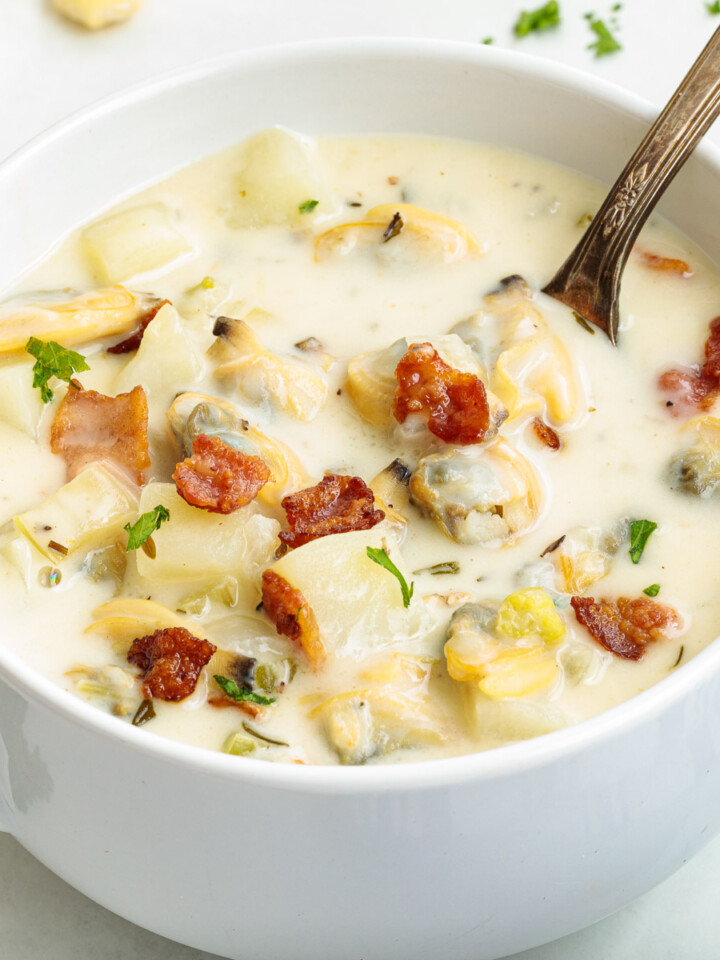 A bowl of New England clam chowder with a spoon resting in the bowl.