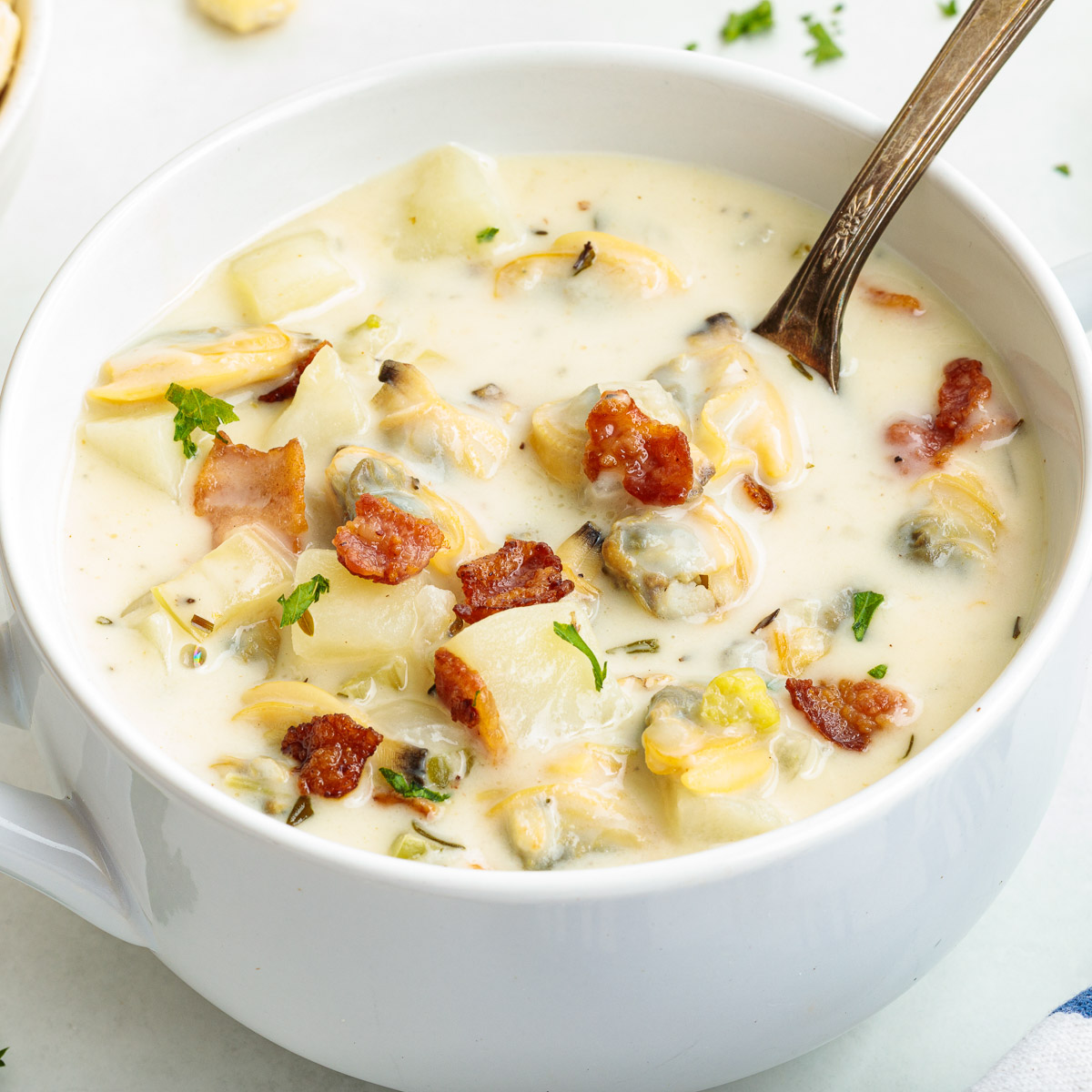 A bowl of New England clam chowder with a spoon resting in the bowl.