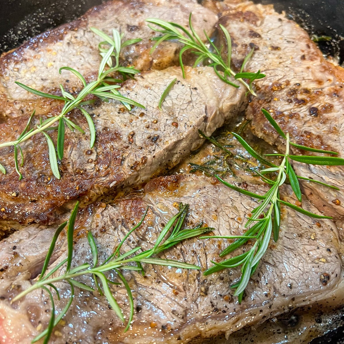 Seared cast iron steak with a golden crust on a cutting board.