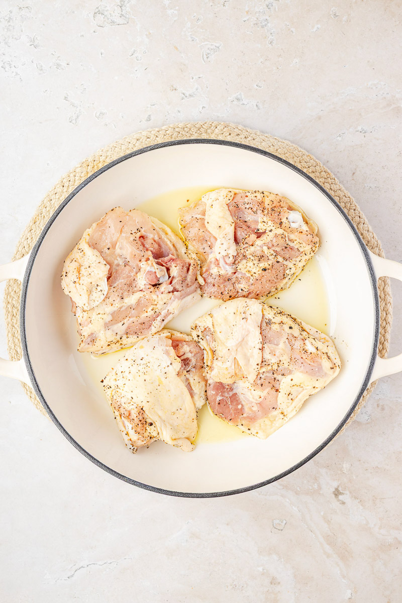 Chicken thighs seasoned and put on the skillet.