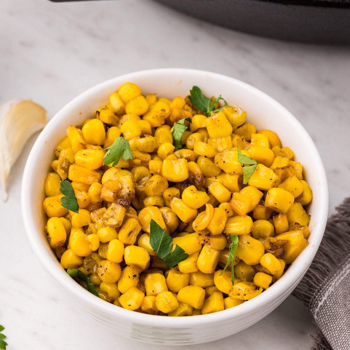 Garlic butter skillet corn served in a white bowl garnished with parsley