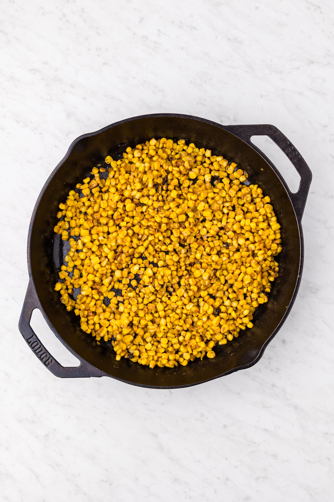Corn developing golden caramelized spots in the cast iron skillet