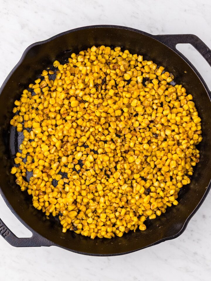 Garlic butter skillet corn with golden caramelized kernels in a Lodge cast iron skillet overhead view