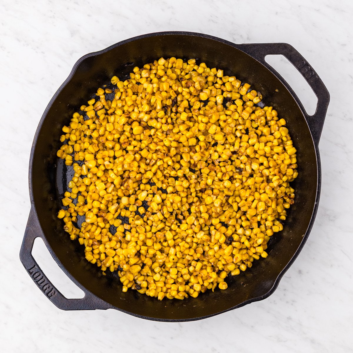 Garlic butter skillet corn with golden caramelized kernels in a Lodge cast iron skillet overhead view