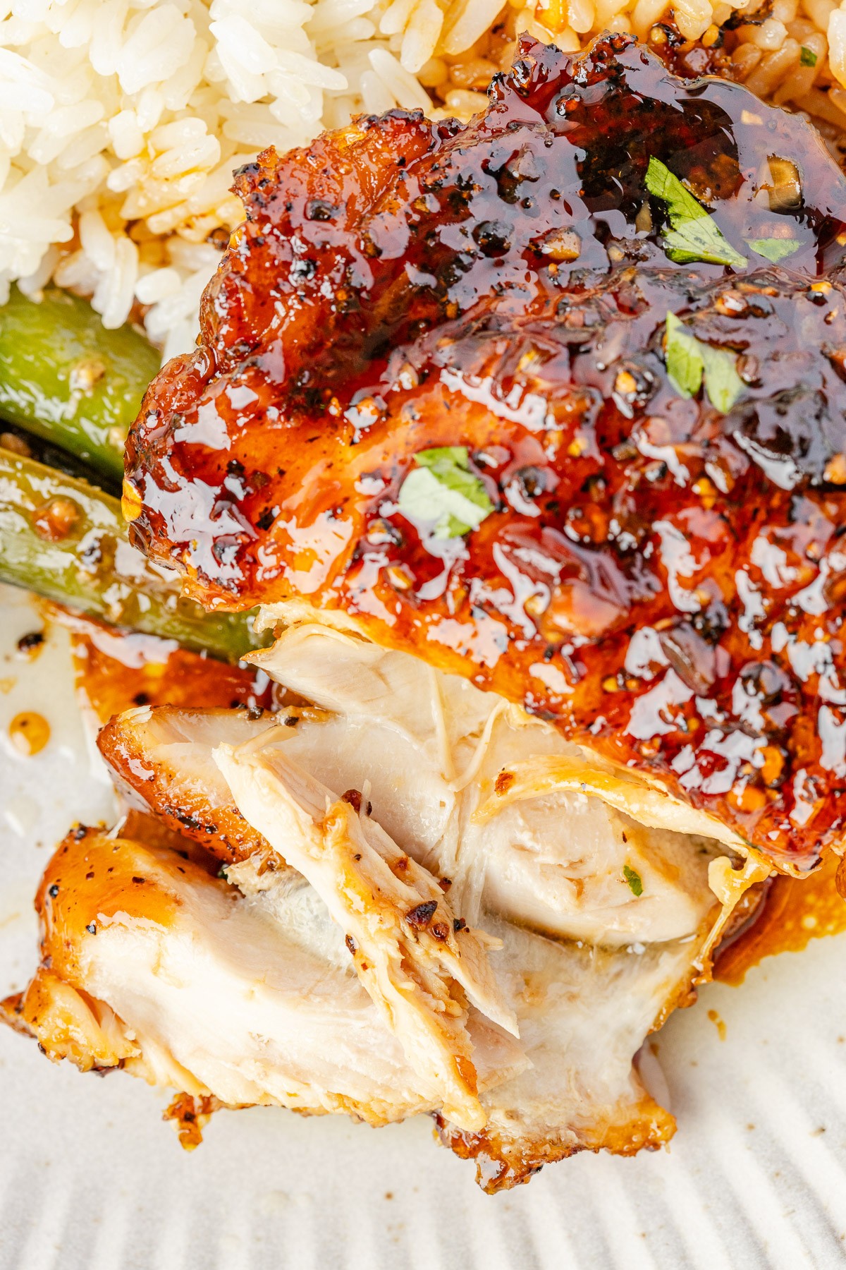 A piece of chicken thighs with honey garlic sauce, with a few pieces cut.