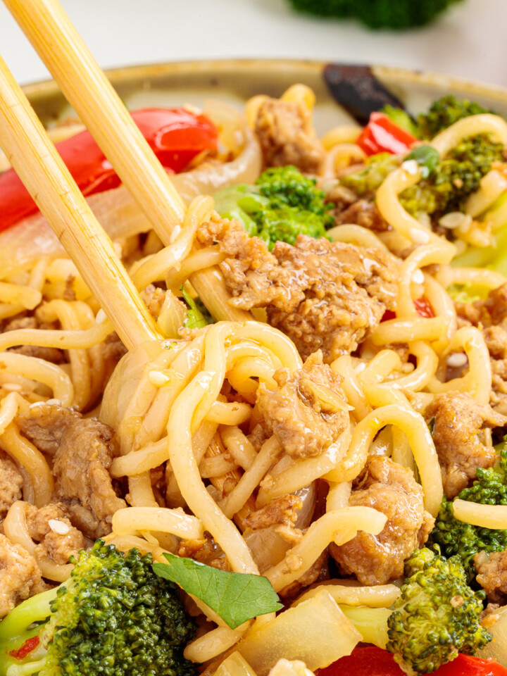 Chopsticks lifting a bite of ground turkey stir fry from a bowl.